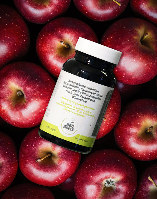 Neoapple Kapseln in einer Dose auf frischen roten Äpfeln
