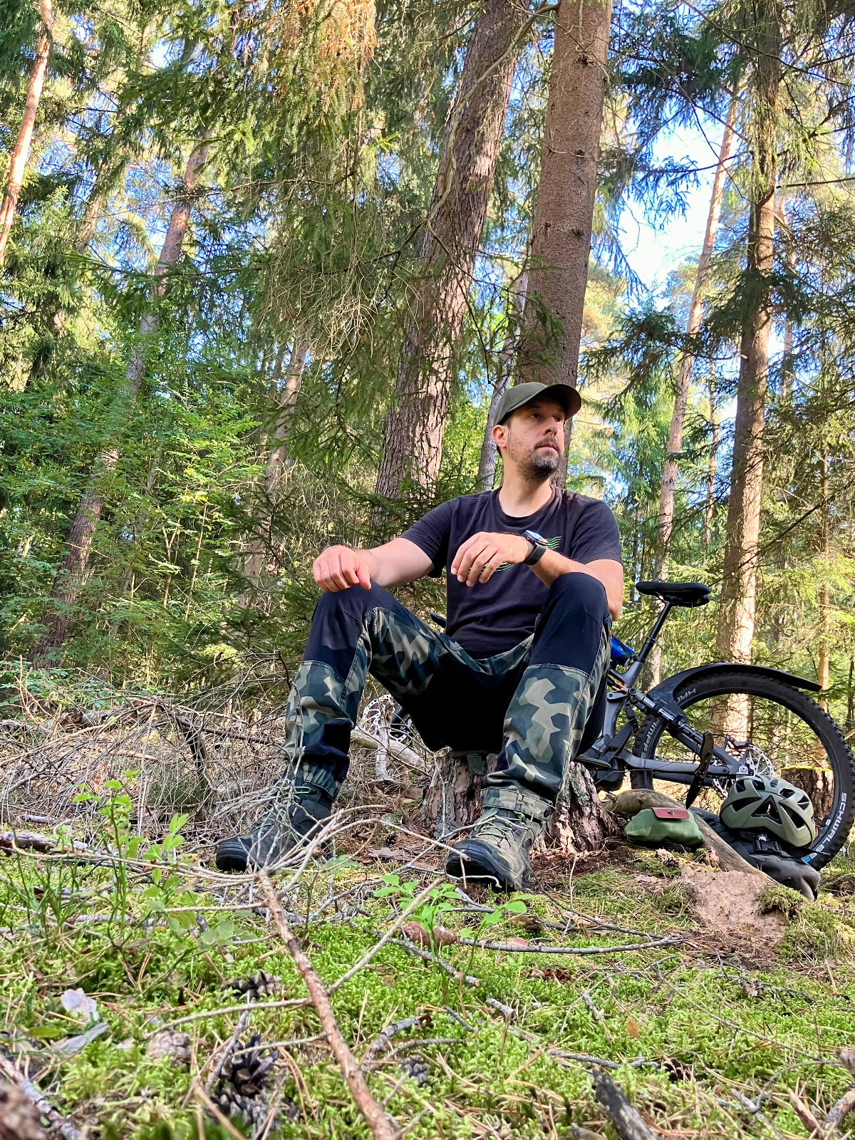 Philipp von Neoapple im Wald sitzend vor einem Mountainbike 