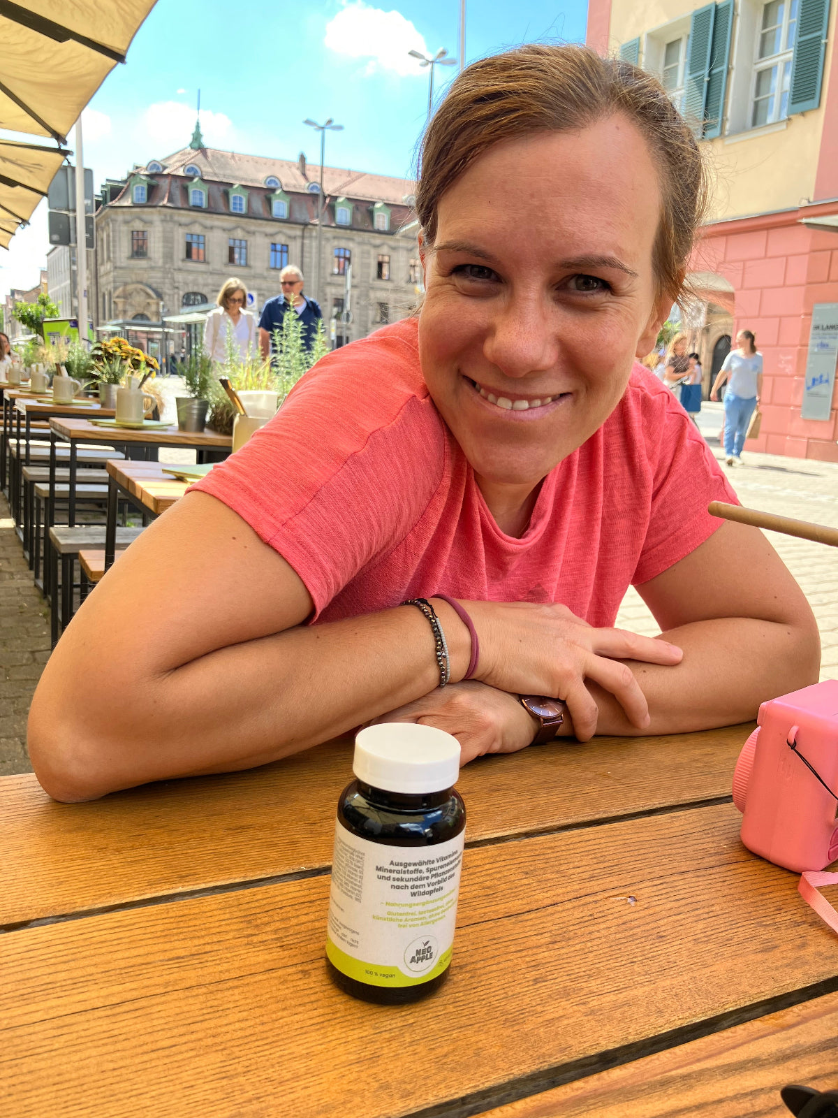 Anna-Lena von Neoapple an einem Café-Tisch mit einer Dose Neoapple Kapseln.