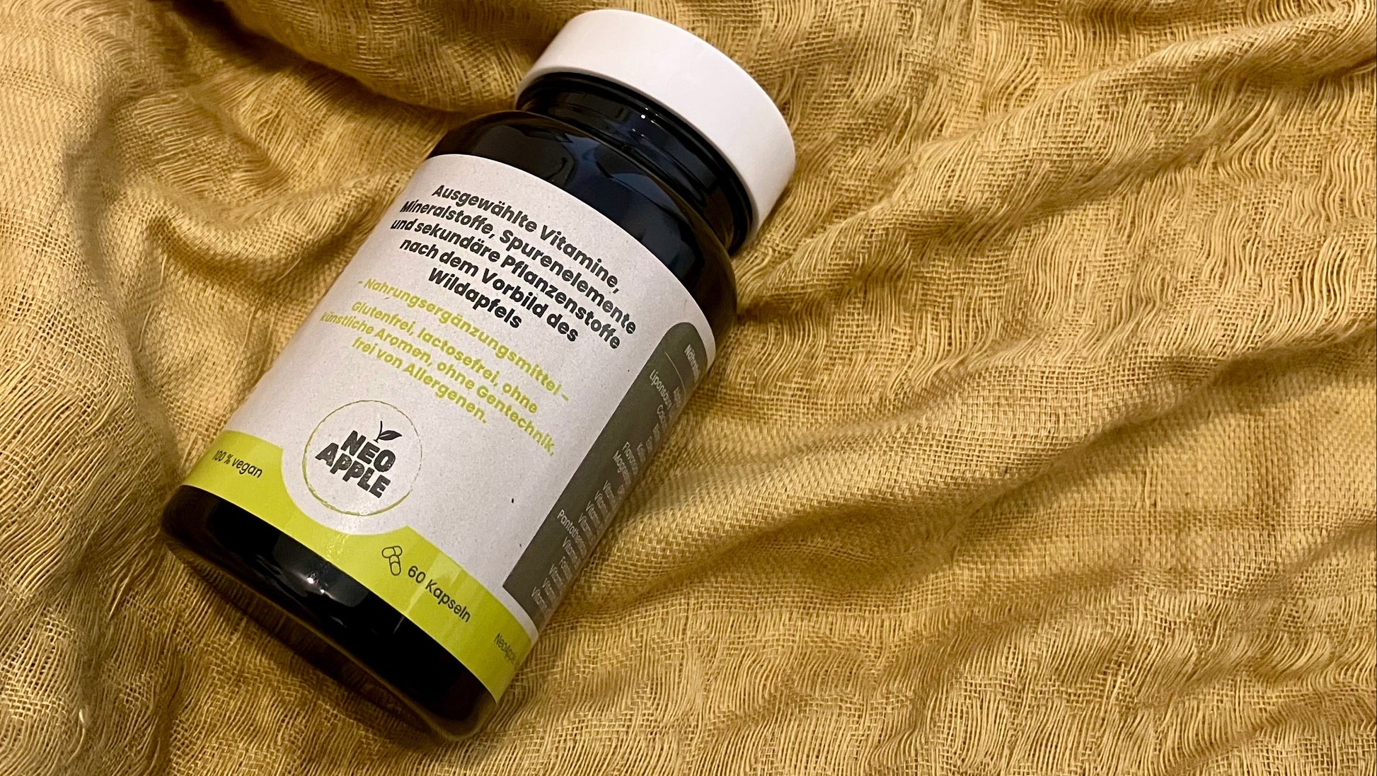 Neoapple Kapseln Dose von Neoapple mit Vitaminen für das Immunsystem und den Energiestoffwechsel auf einem gelben Stofftuch