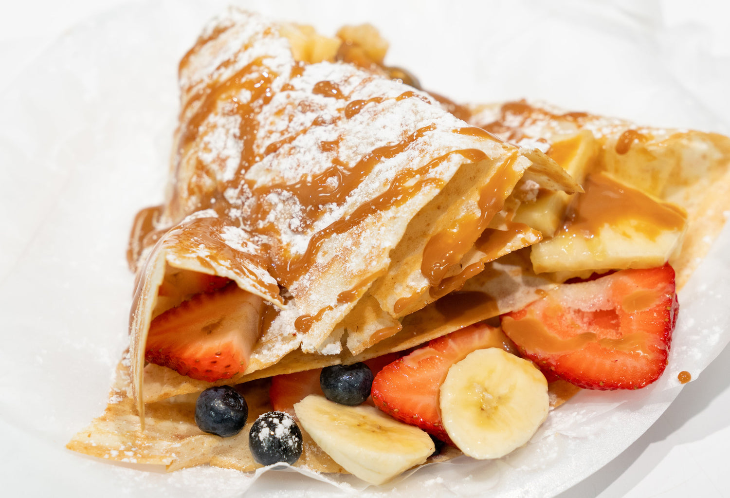 Süßer Crepe mit Obst, bestäubt mit Puderzucker auf einem weißen Untergrund. Steht  symbolisch für Fruchtzucker.