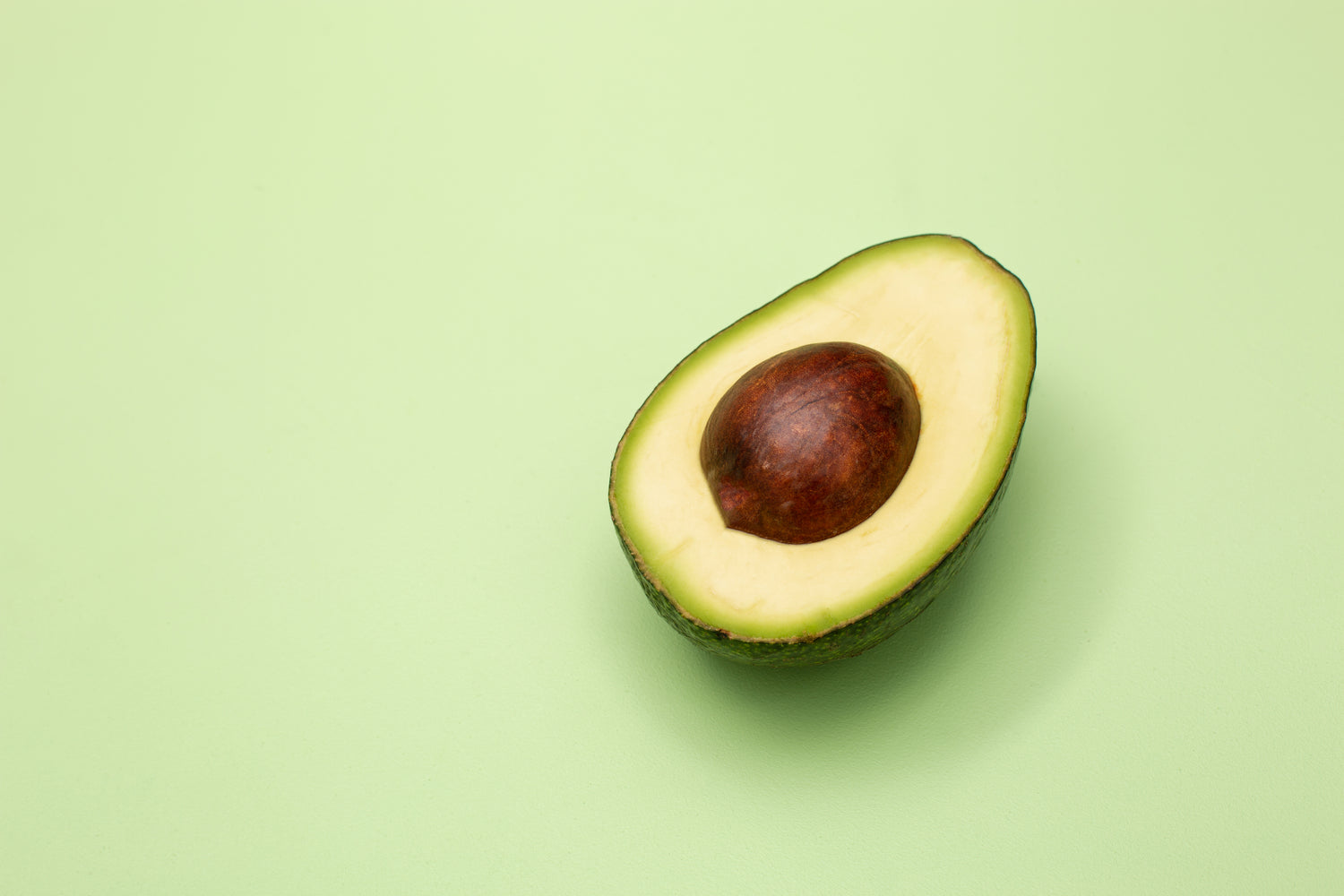Avocado mit viel Vitamin E vor einem grünen fächigen Hintergrund