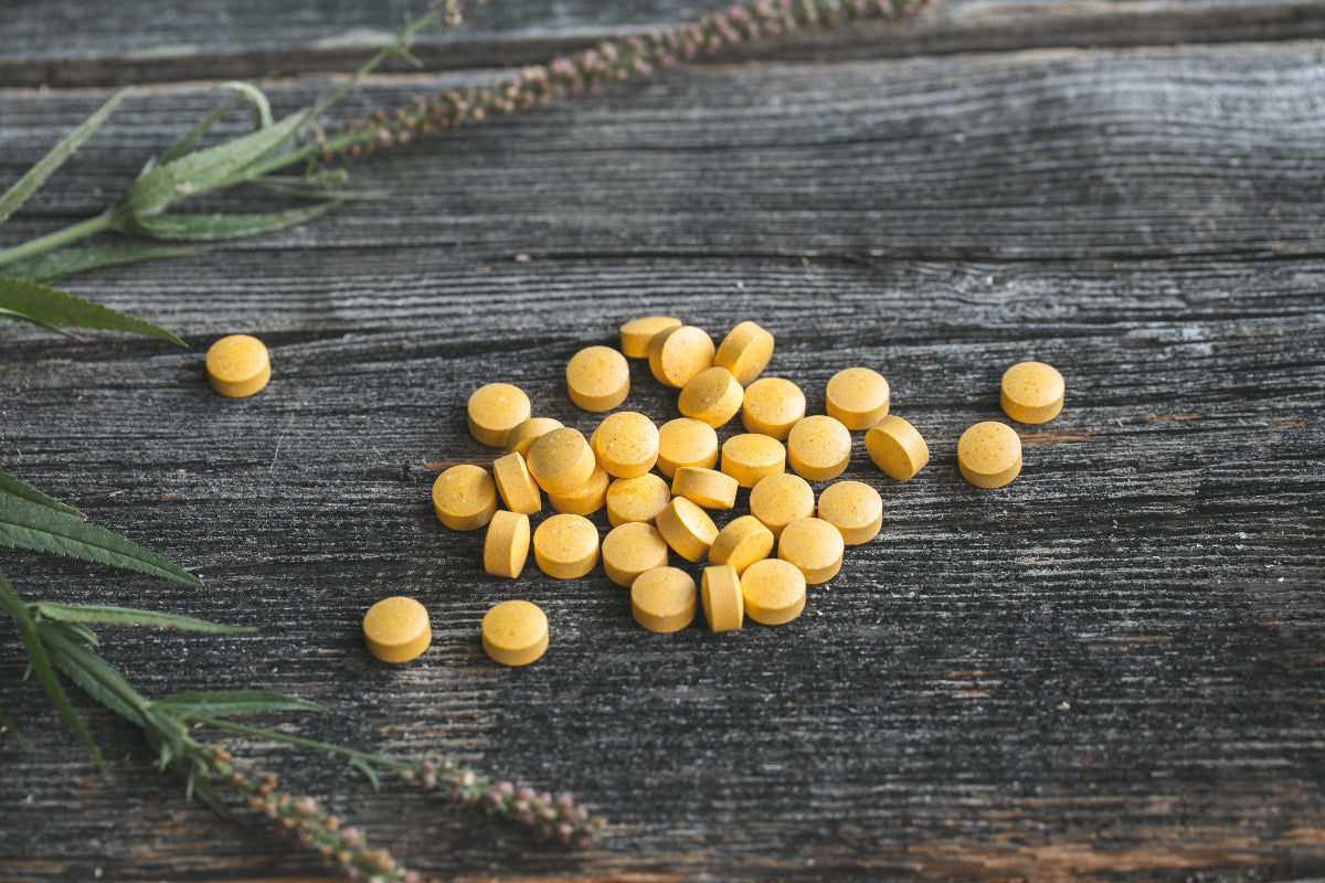 Gelb-orangene Multivitamin-Tabletten auf einem Holztisch.