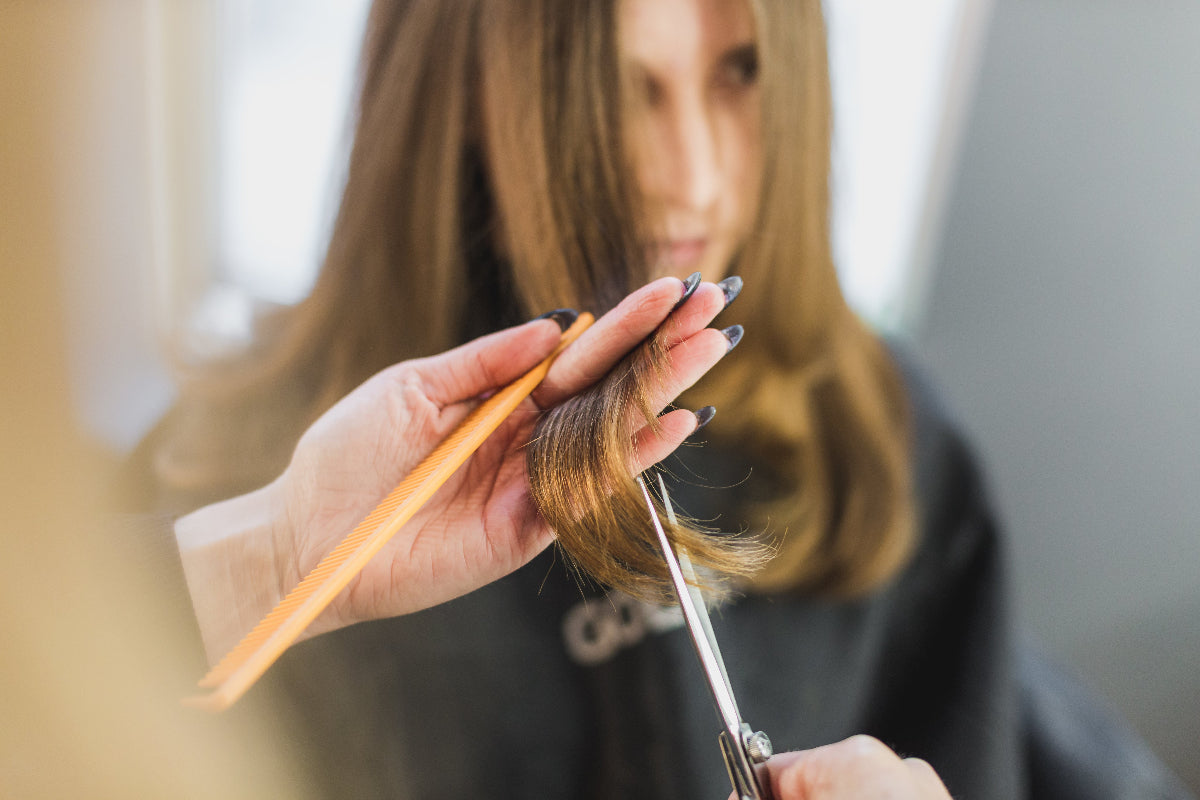 Frau mit langen Haaren beim Friseur: Pantothensäure ist wichtig für das Wachstum und die Pigmentierung der Haare. 